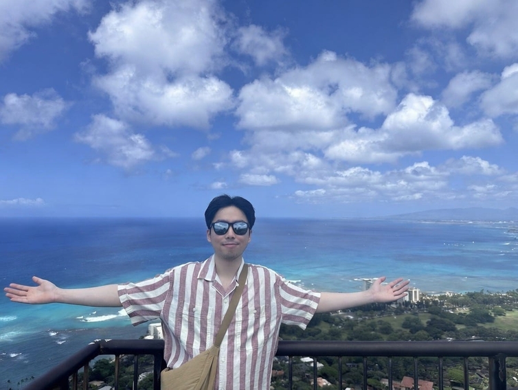 Jonathan with arms outstretched above the ocean coastline of Oahu
