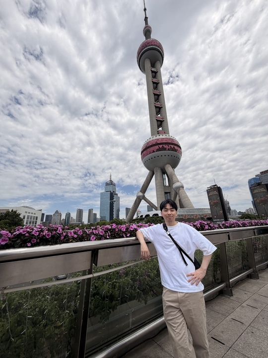 Jonathan leaning on a railing in front of the Oriental Pearl Tower in Shanghai